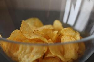 Crispy potato chips in a clear bowl ready for snacking during a casual gathering in the afternoon photo