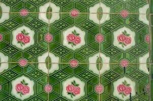 A close up of a weathered floor, featuring ornate, multicolored tiles with a detailed floral pattern, showcasing vintage charm and historical decay photo
