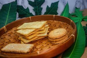 A rustic collection of savory and sweet biscuits, perfect for snacking or a light meal, arranged in a traditional woven basket with natural leaf accents photo