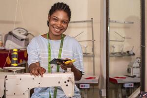 female dressmaker using her phone while working with sewing machine photo