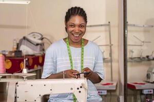 focused female dressmaker using her phone while working with sewing machine photo