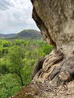 Stone cliff with view of green mountain forest below. Nature background. photo