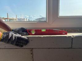 A building level on a window sill during house construction. The builder checks the level of the window sill. photo