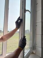 A worker adjusts a plastic window in a new country house. Installing plastic windows in a new building. photo