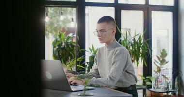 A young woman in casual clothes uses laptop and makes notes in a notebook while sitting at a table in a cafe. Online learning, development and hobbies photo