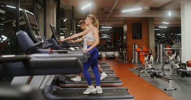 Young man and woman of European appearance, athletic physique, run on a treadmill, working out in a modern gym together photo