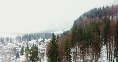 Small European town with cottage development at the foot of a hill with an old castle on top. filming from a quadcopter on a snowy winter day. photo