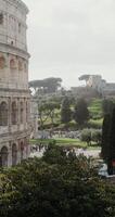 The side of Colosseum and the area in front of the attraction filled with tourists on a sunny clear day. Italy Rome. in 4k, red komodo, vertical photo
