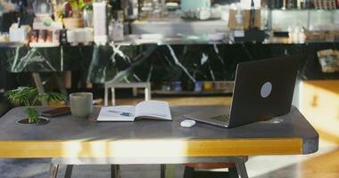 Workplace for remote work in modern stylish coffee shop. An open laptop and a notepad lie on the table in the coworking space photo