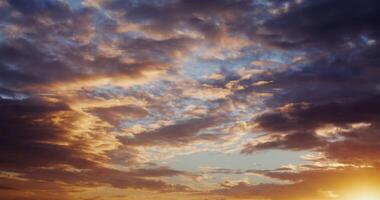 View of sky covered with thick clouds illuminated by the bright light of the rising sun. The bright yellow sun breaks through the clouds. in 4k, red komodo photo