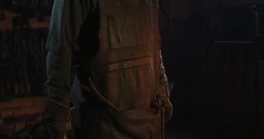 Blacksmith in protective gear and goggles is standing in the workshop photo