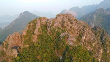 A breathtaking aerial view of a tropical massive mountain peak in Vang Vieng, Laos at sunrise by drone. video