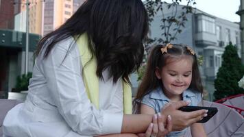 Mother and daughter enjoy time together in the park while using a smartphone video
