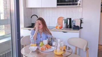 The woman did not get enough sleep, yawns, tries to perk up at breakfast in the kitchen at home in the morning, falls asleep at the table. Lack of sleep, vitamin deficiency, poor health video