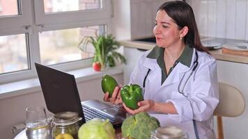 A nutritionist conducts an online consultation with patients at a table with various fruits and vegetables. Avocado and green pepper. Nutrition concept, medical center, fitness. video
