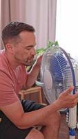 Close-up of a man relaxing under a fan on a hot day. The stuffiness forces her to look for ways to cool down and feel comfortable. video