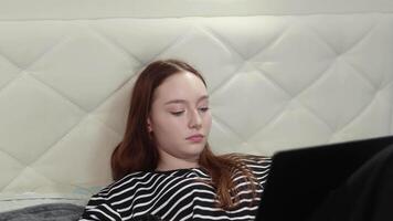 Teenage girl using laptop in bed browsing internet social media relaxing home leisure technology generation z digital native online communication studying working watching movie series calling video