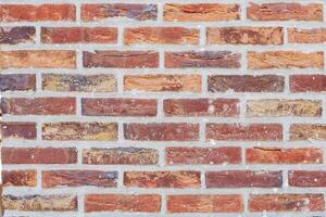 A wall of bricks in different shades of red and brown with repeating pattern of stretcher bricks, attractive textured background in rustic style photo