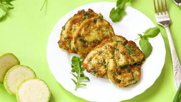 vegetable pancakes from zucchini with green onions in a plate on a green background video