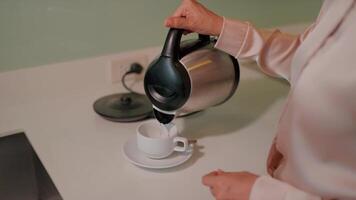 Close up of a person preparing tea bags next to a fancy electric kettle, capturing the everyday simplicity of that moment. video