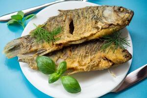 Appetizing fried crucian carp with butter and spices in a frying pan photo