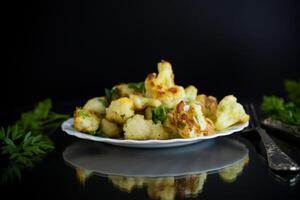Fried cauliflower with spices and herbs on a black background photo