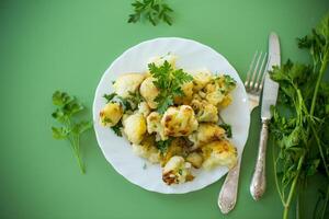 Vegetable dish of fried cabbage with aromatic spices on a green background. photo