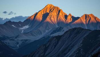 a jagged mountain range illuminated by the first light of day, with shadows cascading down the rocky faces. photo