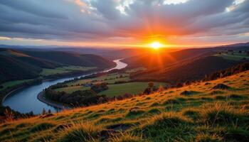 a grassy hill overlooking a winding river that glows orange in the fading light of dusk. photo