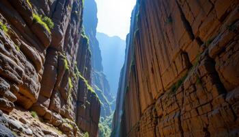 a narrow ravine with towering stone walls lit by a single shaft of sunlight breaking through above. photo