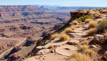 a high canyon rim lined with stone ledges and tufts of dry grass, overlooking an endless plain. photo