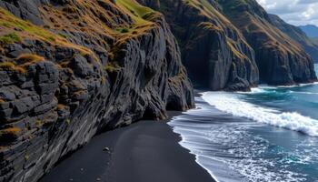 jagged basalt cliffs rising from black sand beach photo