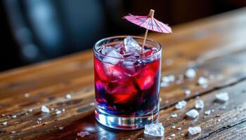 a cocktail with blue liquid, a tiny umbrella, and crushed ice. photo