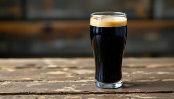 a dark stout poured into a pint glass on wood. photo