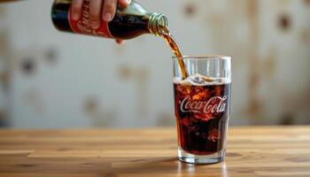 a fizzy cola pouring into a branded glass. photo