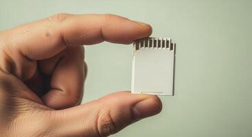 Human hand holding a white SD card, a compact digital memory storage device for modern technology. photo