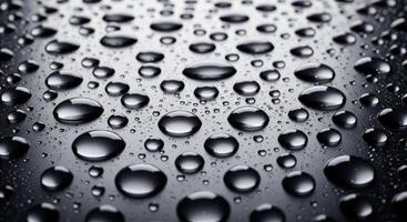 Close up of clear water droplets on a dark wet surface creating a textured abstract background photo