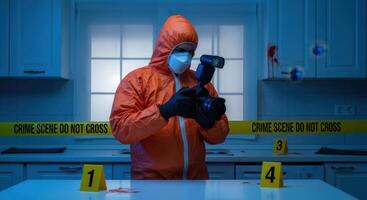 Forensic investigator in protective suit photographs evidence at a crime scene with police tape. photo