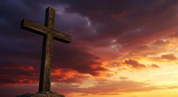 Wooden cross silhouetted against a dramatic and colorful sunset sky with vibrant clouds photo