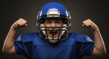 Young boy in blue football helmet flexing muscles and shouting with determination. photo