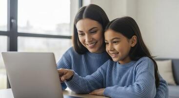 Smiling mother and daughter bonding while looking at a laptop screen together at home. photo