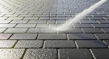Pressure washing dark grey brick patio pavers, effectively cleaning dirt and moss from the surface. photo