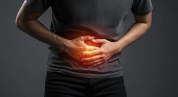 Man experiencing severe stomach pain, clutching his abdomen with hands, indicating discomfort. photo