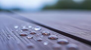 Glistening dew drops on dark weathered mahogany wood surface in a detailed macro shot. photo