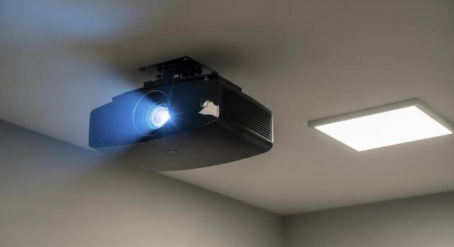 Modern black projector mounted on a light grey ceiling with a bright light beam and LED panel photo