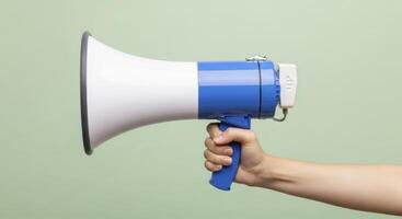 Human hand holding a blue and white megaphone for communication and public announcement photo