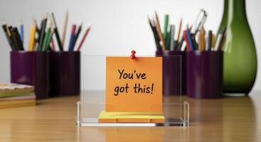 Motivational orange sticky note message on an office desk with supplies. photo