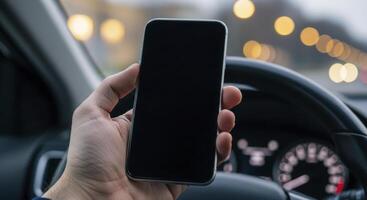 Hand holding a smartphone with a blank screen inside a car, with blurred city lights. photo