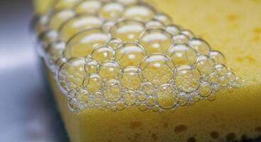 Macro view of soap bubbles on a yellow sponge for cleaning and hygiene concepts. photo