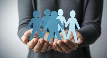 Hands holding light blue paper cut out figures symbolizing community and social support photo